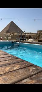 a swimming pool with a chair in front of a pyramid at Pyramids Height Hotel & Pyramids Master Scene Rooftop in Cairo