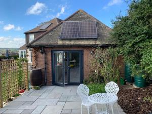 a patio with a table and chairs in front of a house at Cosy Valley-View Cottage - Hot Tub, Free Parking, Countryside Views in Barham