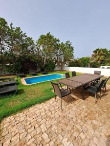 a picnic table and chairs next to a swimming pool at Spacious family friendly 3-Bed Villa Dunas Resort in Santa Maria