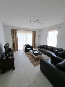 uma sala de estar com sofás pretos e uma televisão em Spacious family friendly 3-Bed Villa Dunas Resort em Santa Maria