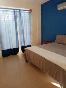 1 dormitorio con 1 cama con paredes y cortinas azules en Altamar en Zihuatanejo