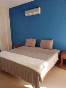 Un dormitorio con una pared azul y una cama en Altamar, en Zihuatanejo