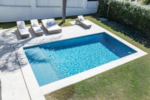 einen Pool mit 2 Liegestühlen und einem Pool in der Unterkunft Villa Casiopea- Stunning holiday villa in Marbella in Marbella