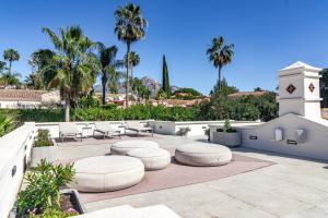 eine Terrasse mit Stühlen, Tischen und Palmen in der Unterkunft Villa Casiopea- Stunning holiday villa in Marbella in Marbella