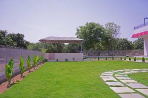 een tuin met een tuinhuisje en een groen gazon bij Green Mango Farmhouse in Chityāl