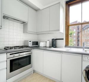 倫敦的住宿－Lovely Spot by City of London，白色的厨房配有白色橱柜和窗户