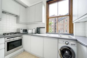 cocina con lavadora y fregadero en Lovely Spot by City of London en Londres