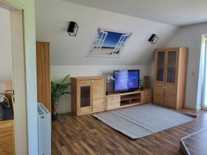 uma sala de estar com uma televisão de ecrã plano e armários de madeira em Komplette 4 Zimmer OG Wohnung em Langwedel