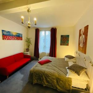 a bedroom with a bed and a red couch at Mirepoix Labyrinthe chambre avec salle de bain et lit 180 cm in Mirepoix