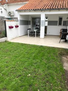 a house with a patio with a table in the yard at jolie maison de bourg in Arvert