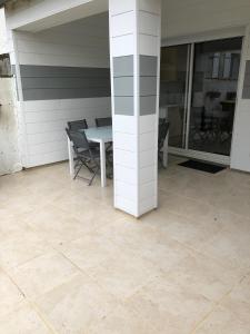 a patio with a table and chairs on a tile floor at jolie maison de bourg in Arvert
