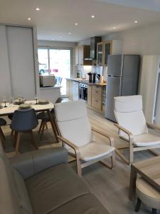 a kitchen with white chairs and a table and a kitchen with a refrigerator at jolie maison de bourg in Arvert
