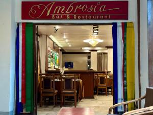 un restaurant avec des tables et des chaises et un panneau coloré dans l'établissement HOTEL RENDEZVOUS, à Gangtok