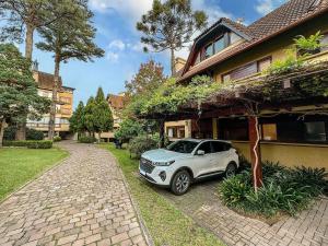 a white car parked in front of a house at Villa Del Fiori com Piscina Aquec by Achei Gramado in Gramado