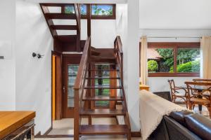 a wooden spiral staircase in a room with a table at Villa Del Fiori com Piscina Aquec by Achei Gramado in Gramado