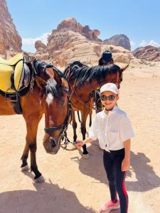 a young girl standing next to a horse in the desert at Petra Royal Ranch in Wadi Musa