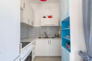 a small kitchen with white cabinets and blue shelves at Villa Maria in Néa Michanióna