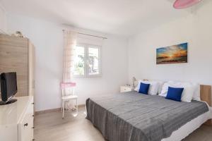 a bedroom with a bed with blue pillows and a tv at Villa Maria in Néa Michanióna +19 photos