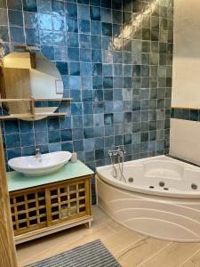 a blue tiled bathroom with a tub and a sink at El Rincón de Victoria y Manolo in Sotillo de la Adrada