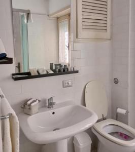 uma casa de banho branca com um lavatório e um WC em gaia em Terracina