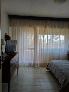 um quarto com uma cama, uma televisão e uma janela em gaia em Terracina