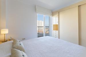 ein weißes Schlafzimmer mit einem großen Bett und einem Fenster in der Unterkunft AG Salinas 9 in Playa de Gandia + 31 Fotos