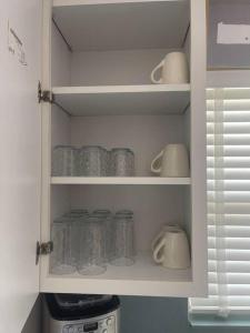 a kitchen cabinet filled with glass jars and mugs at Salty Bones, Hemingway-esque Florida Escape, Boat On Property in Matlacha