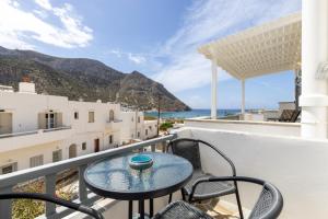 balcón con mesa, sillas y vistas al océano en Litsa Rooms, en Kamarai