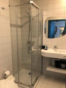 a bathroom with a glass shower and a sink at HOTEL LEHOUCK in Koksijde