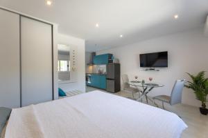 カシュテラにあるModerni studioのキッチンとリビングルームがあり、部屋には大きな白いベッドがある