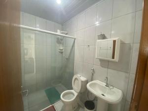 a white bathroom with a toilet and a sink at Frente ao mar casa 40 Praia do Estaleiro in Ubatuba +8 photos