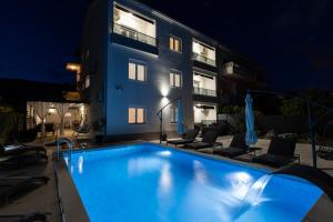 a swimming pool in front of a building at night at Apartments Bilopavlović in Kaštela