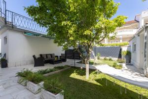 a patio with a tree and a couch in a yard at Apartments Bilopavlović in Kaštela