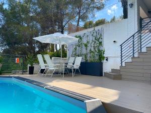 eine Terrasse mit einem Tisch und einem Sonnenschirm neben einem Pool in der Unterkunft TERRAVU in Sant Pere de Ribes