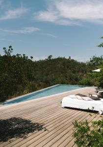 1 cama en una terraza de madera junto a la piscina en The ONE - Country House, en Grândola