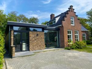 una casa con grandes puertas de cristal y un edificio de ladrillo en Villa Royale, en Oranjewoud