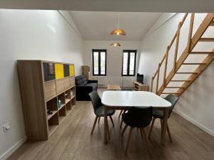 ein Wohnzimmer mit einem Tisch, Stühlen und einer Treppe in der Unterkunft Grand Studio Duplex Stade France in Aubervilliers