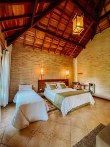a bedroom with two beds and a wooden wall at Pousada Bucaneve in Monte Verde