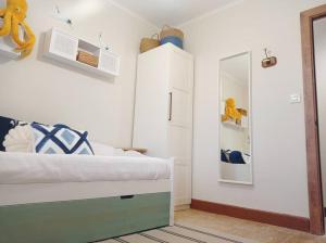 ein weißes Schlafzimmer mit einem Bett und einem Spiegel in der Unterkunft Erizana in Baiona