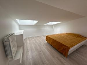 ein Schlafzimmer mit einem Bett in einem Zimmer mit Oberlichtern in der Unterkunft Grand Studio Duplex Stade France in Aubervilliers