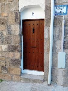 una puerta de madera en un edificio de piedra con una señal en Calle Larga 43/2, en La Adrada