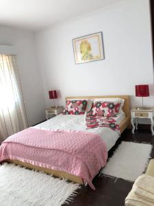 a bedroom with a bed with a pink blanket and two tables at Casa do Trevo in Salir do Porto