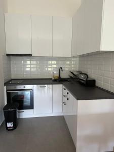 a kitchen with white cabinets and a black counter top at Apartman 103 in Vrdnik +2 photos
