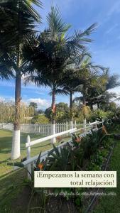 una valla blanca con palmeras en el fondo en Finca Hotel 12 Palmas- Aeropuerto JMC, en Rionegro