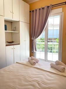 uma cama com duas toalhas num quarto com uma janela em Your Home In Elefsis em Elêusis