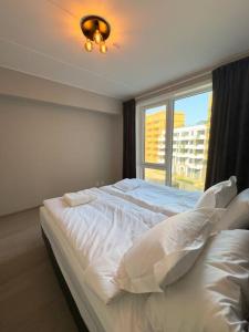 a bedroom with a large white bed with a window at Moderne 3 Roms leilighet i Oslobukta! in Oslo