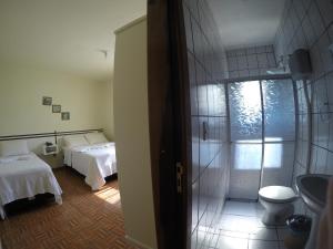a bathroom with two beds and a toilet in a room at Hotel Schreiber in Rio do Sul