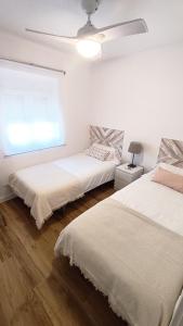 2 Betten in einem weißen Zimmer mit Fenster in der Unterkunft Puerto Placilla in El Puerto de Santa María