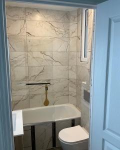 y baño con bañera blanca y aseo. en Appartement F3, proche paris en Épinay-sur-Seine