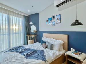Căn hộ The Sóng Vũng Tàu في فنغ تاو: غرفة نوم بسرير مع جدار ازرق